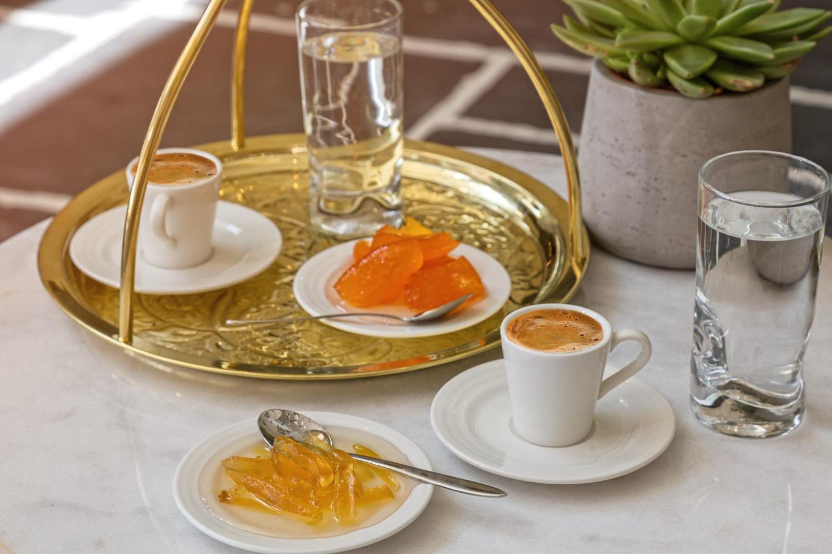Grieķu kafijas servējums Amada Colossos Resort ar tradicionāliem saldumiem uz zelta paplātes un glāzi ūdens