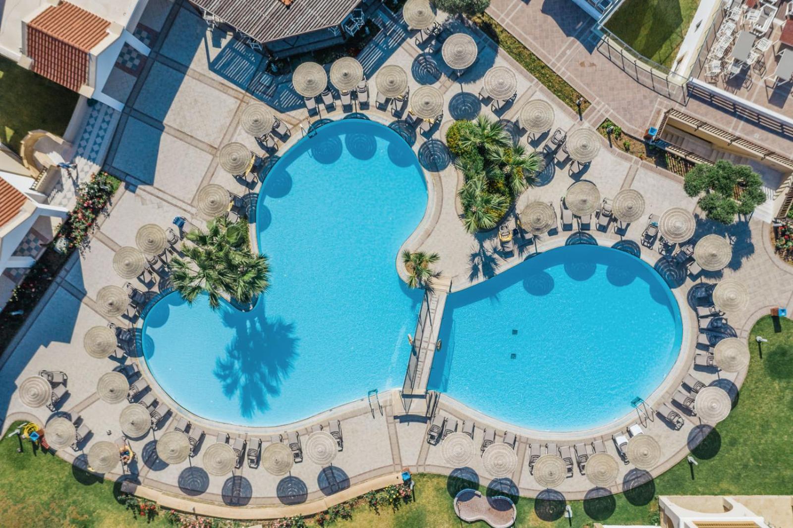 Lindos Imperial Resort & SPA galvenais āra baseins Rodas salā — skats no augšas uz zilo ūdeni, saulessargiem un atpūtas zonu