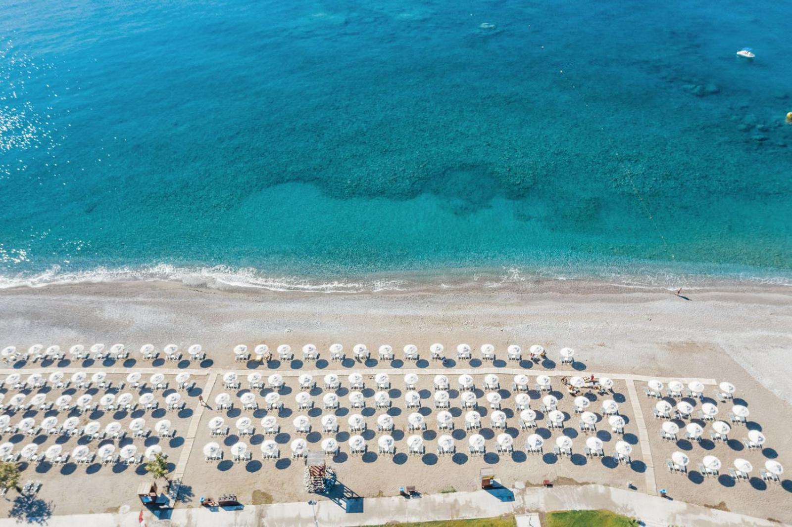Lindos Imperial Resort & SPA privātā pludmale ar dzidru, tirkīzzilu ūdeni un sakārtotām saulessargu rindām Rodas salas piekrastē