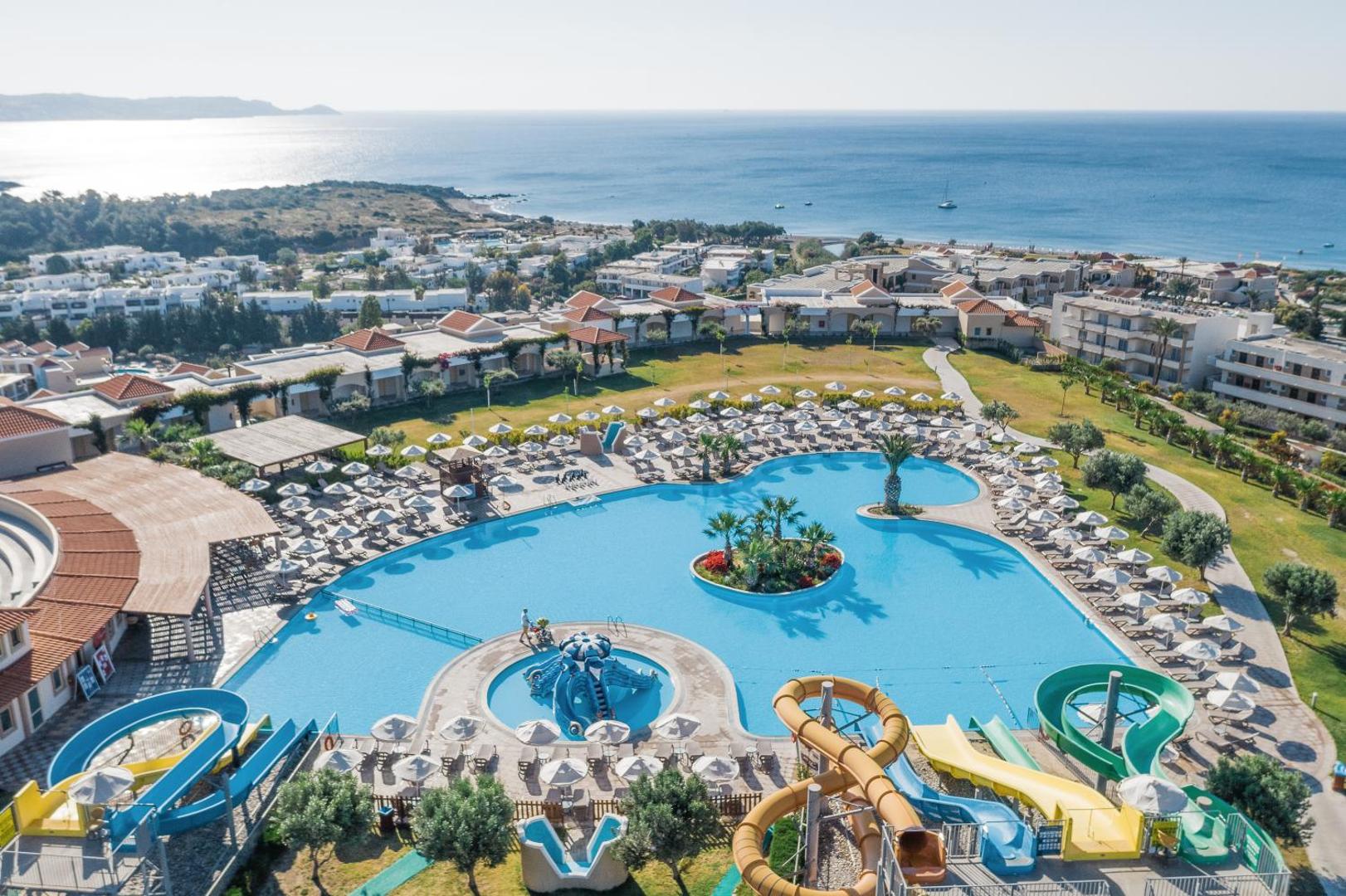 Lindos Imperial Resort & SPA galvenais baseins ar ūdens slidkalniņiem Rodas salā — plaša atpūtas zona ar saulessargiem un skatu uz jūru