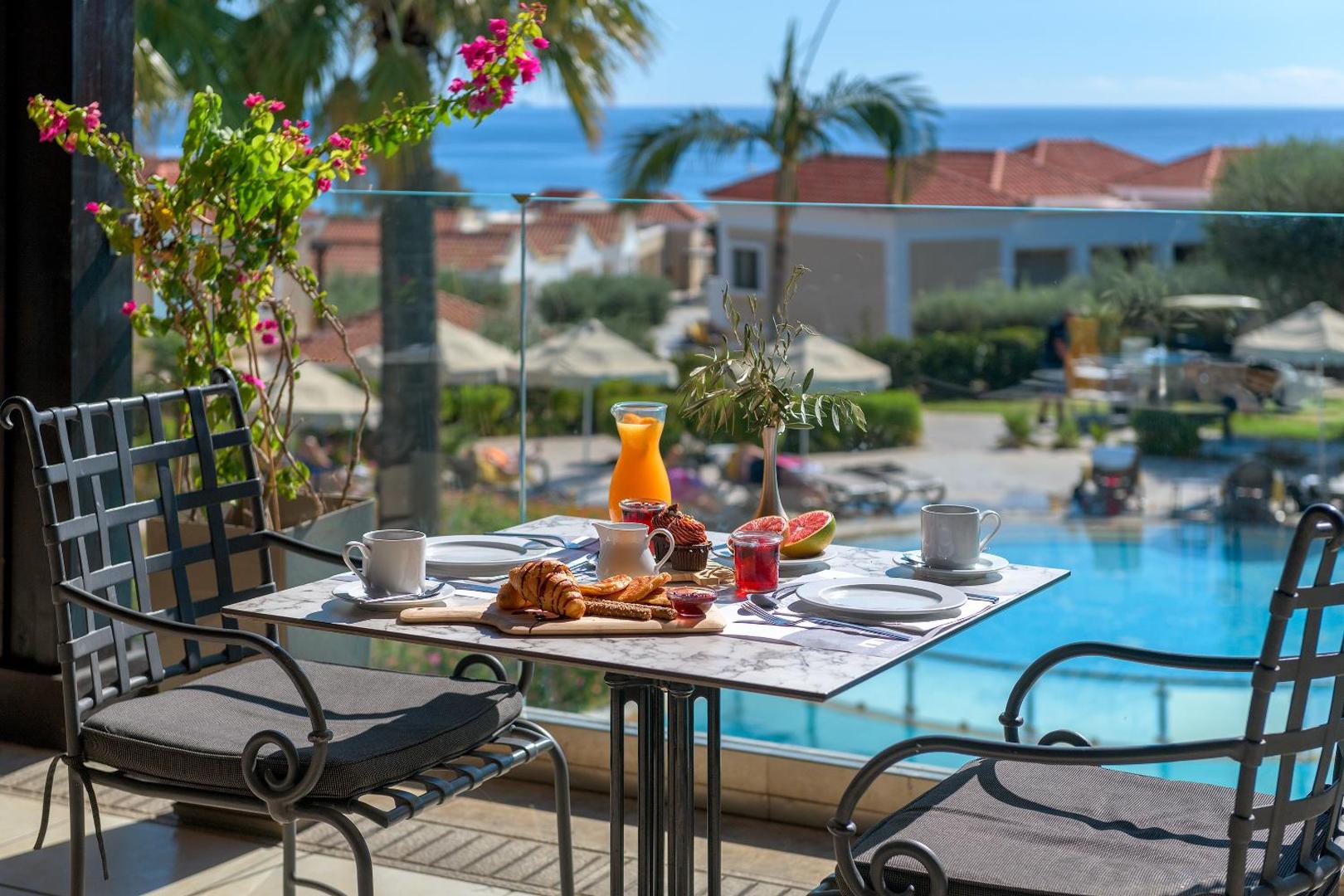 Lindos Imperial Resort & SPA brokastu galds uz terases ar skatu uz baseinu, palmām un Vidusjūru Rodā