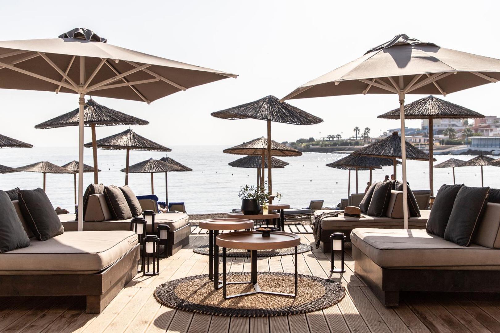 Eden Roc Resort pludmales atpūtas zona ar mīkstiem dīvāniem, saulessargiem un skatu uz jūru saulainā dienā
