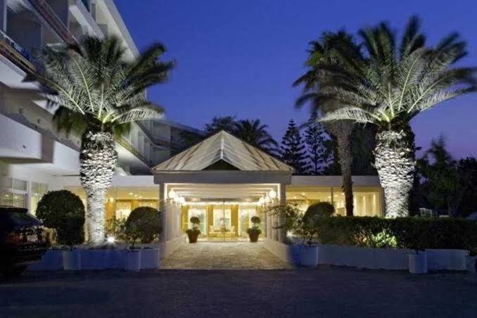 Eden Roc Resort galvenā ieeja vakarā ar izgaismotām palmām un modernu stikla nojumi Rodas kūrortā