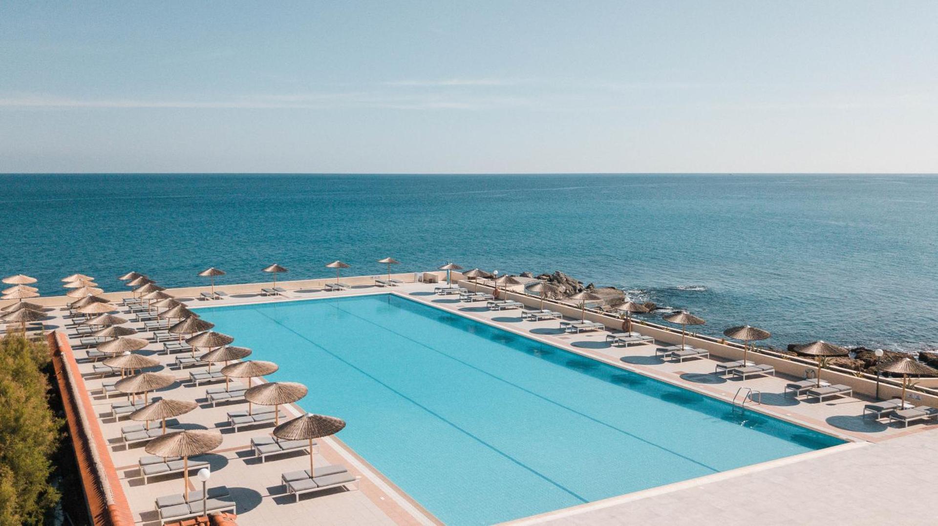 Eden Roc Resort lielais āra baseins tieši pie Egejas jūras krasta ar sauļošanās krēsliem un saulessargiem Rodas salā.