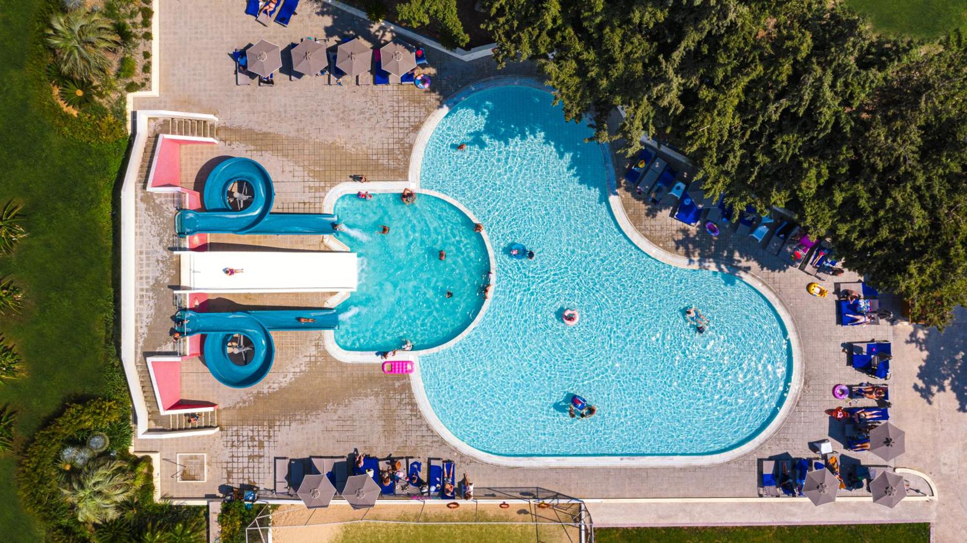Eden Roc Resort akvaparka baseins ar ūdens slidkalniņiem no putna lidojuma, apkārt esošo atpūtas zonu un kokiem.
