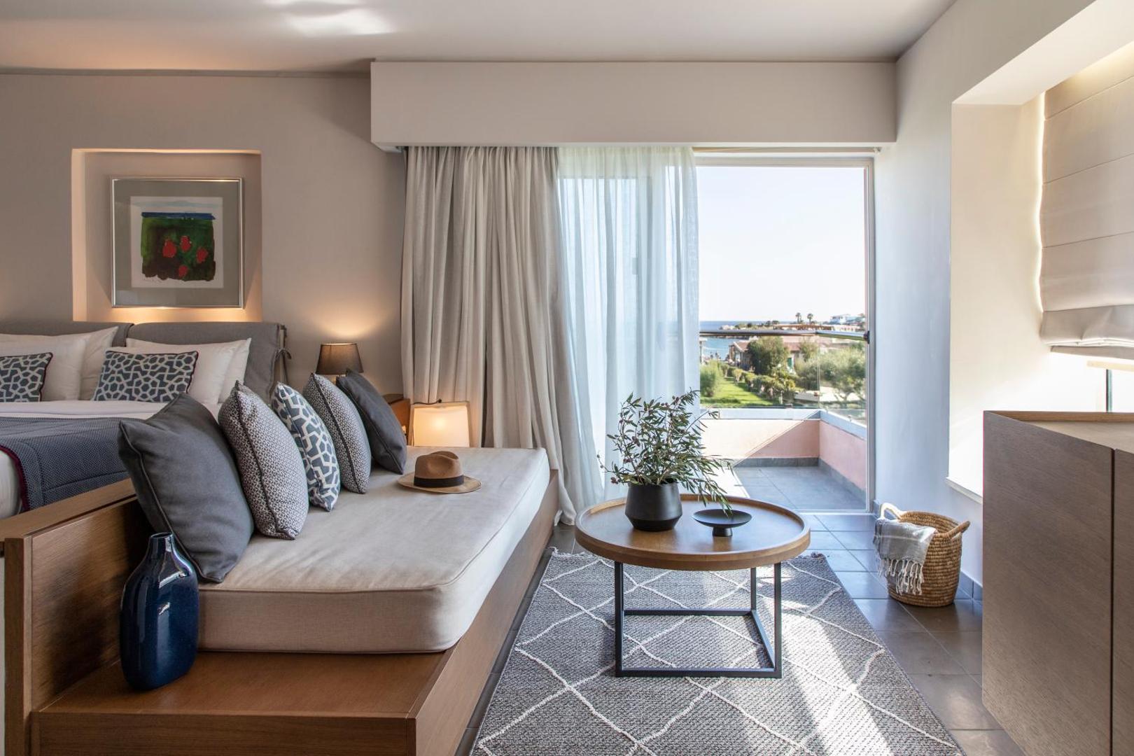 Moderns Eden Roc Resort numurs ar atpūtas zonu, dīvānu un balkonu, no kura paveras skats uz dārzu