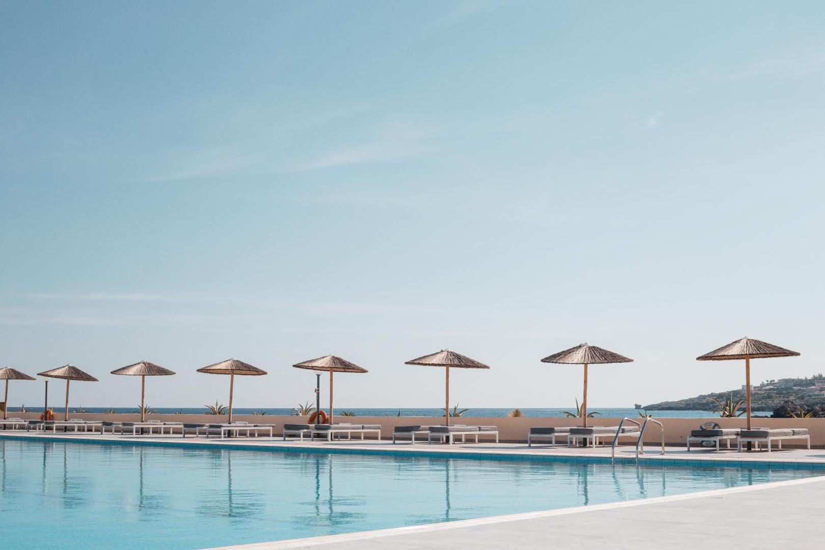 Eden Roc Resort plašais āra baseins ar skatu uz jūru Rodā — saulessargi un sauļošanās krēsli pie zilā ūdens horizonta