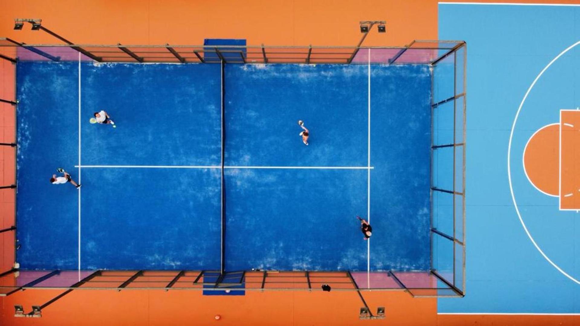 Eden Roc Resort sporta infrastruktūra no putna lidojuma — zils padela tenisa kortas un basketbola laukums Rodas kūrortā