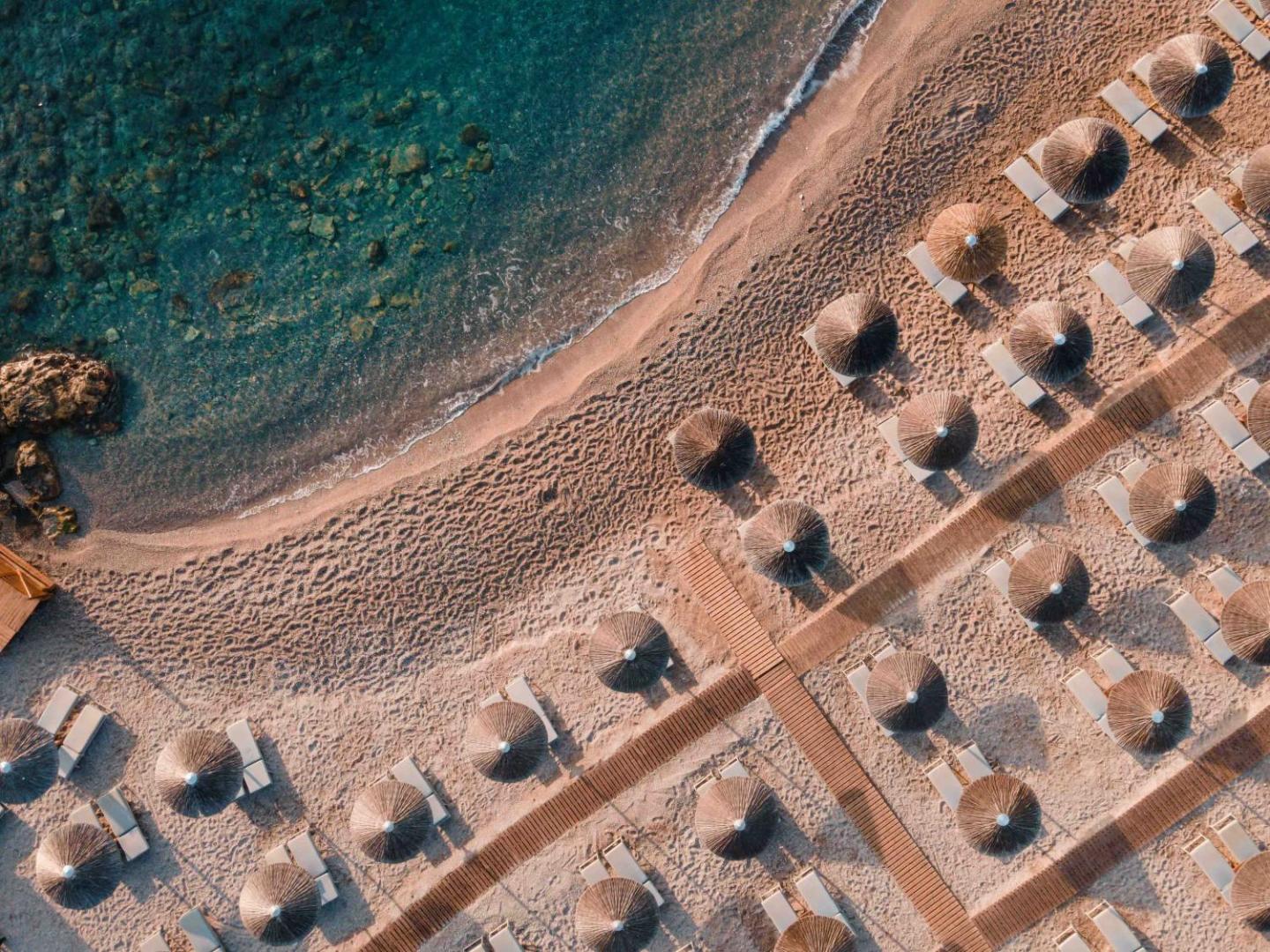 Aerofoto skats uz Eden Roc Resort privāto smilšu pludmali, saulessargiem un dzidru tirkīza krāsas ūdeni Rodas piekrastē