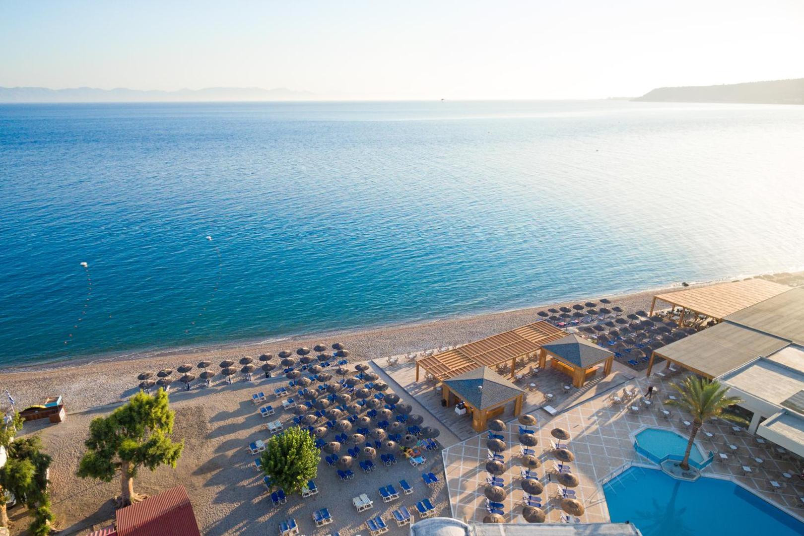 Aerofoto skats uz Avra Beach Resort privāto pludmali ar saulessargiem, bāru un dzidro jūras ūdeni Rodas piekrastē