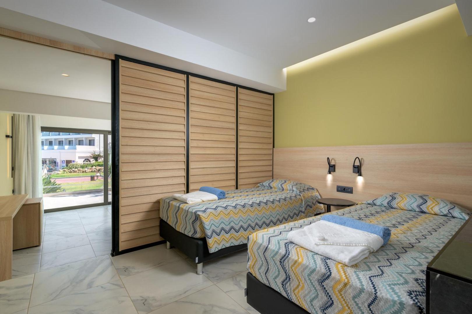 Avra Beach Resort Hotel & Bungalows numurs ar divām atsevišķām gultām, koka bīdāmajām durvīm un gaiši zaļu sienu
