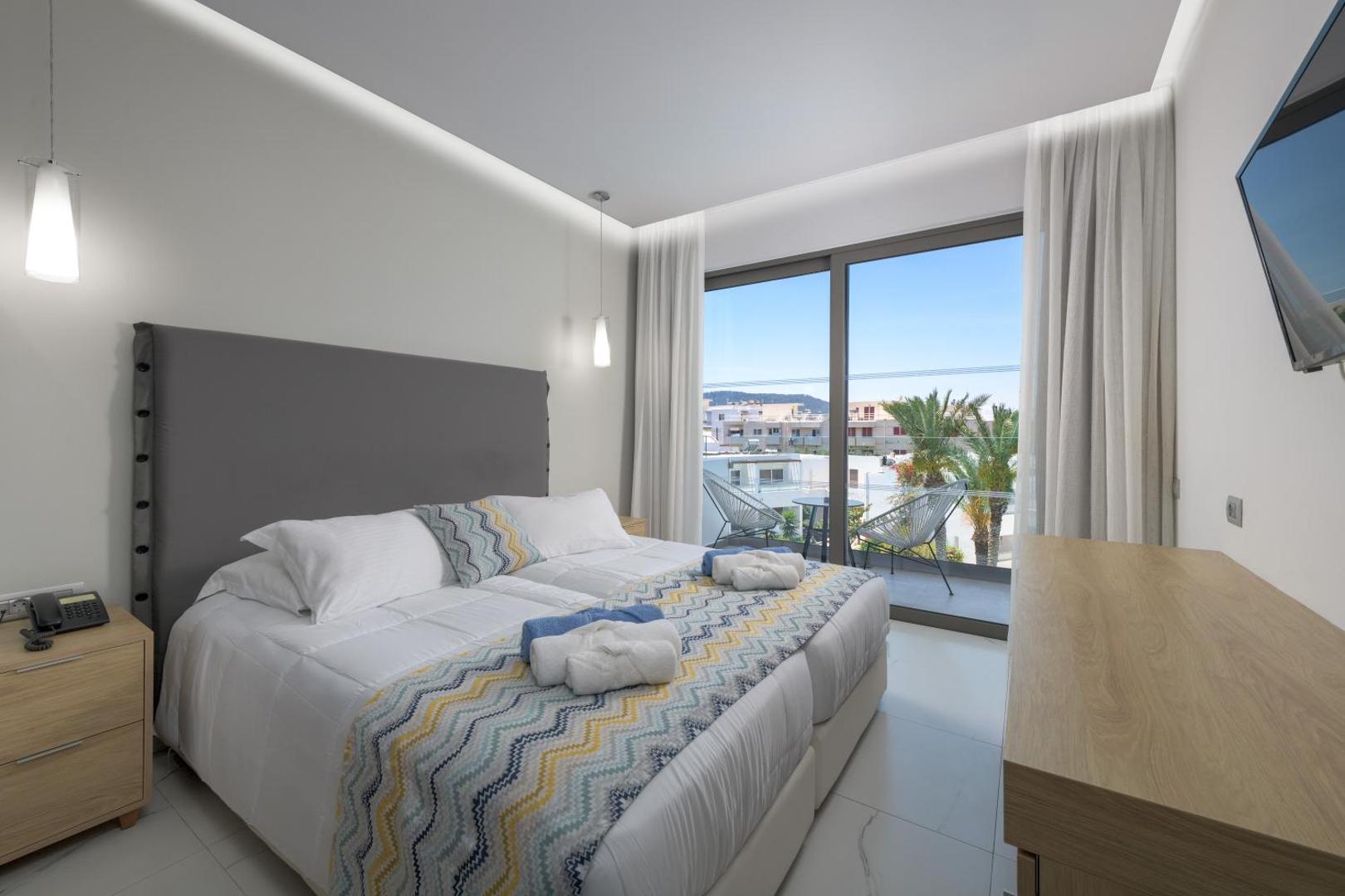 Avra Beach Resort Hotel & Bungalows divvietīgs numurs ar pelēku galvgali, modernu apgaismojumu un skatu uz pilsētas ainavu