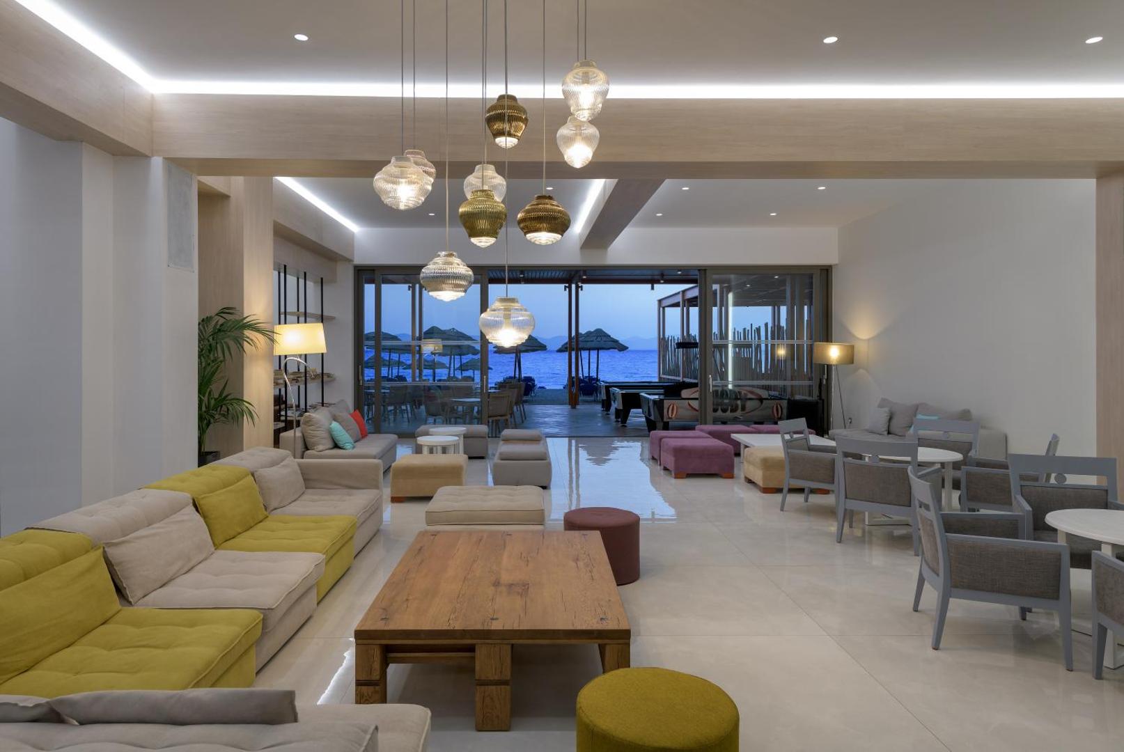 Avra Beach Resort Hotel & Bungalows plašā atpūtas zona ar krāsainiem dīvāniem, dizaina gaismekļiem un skatu uz jūru vakara stundā
