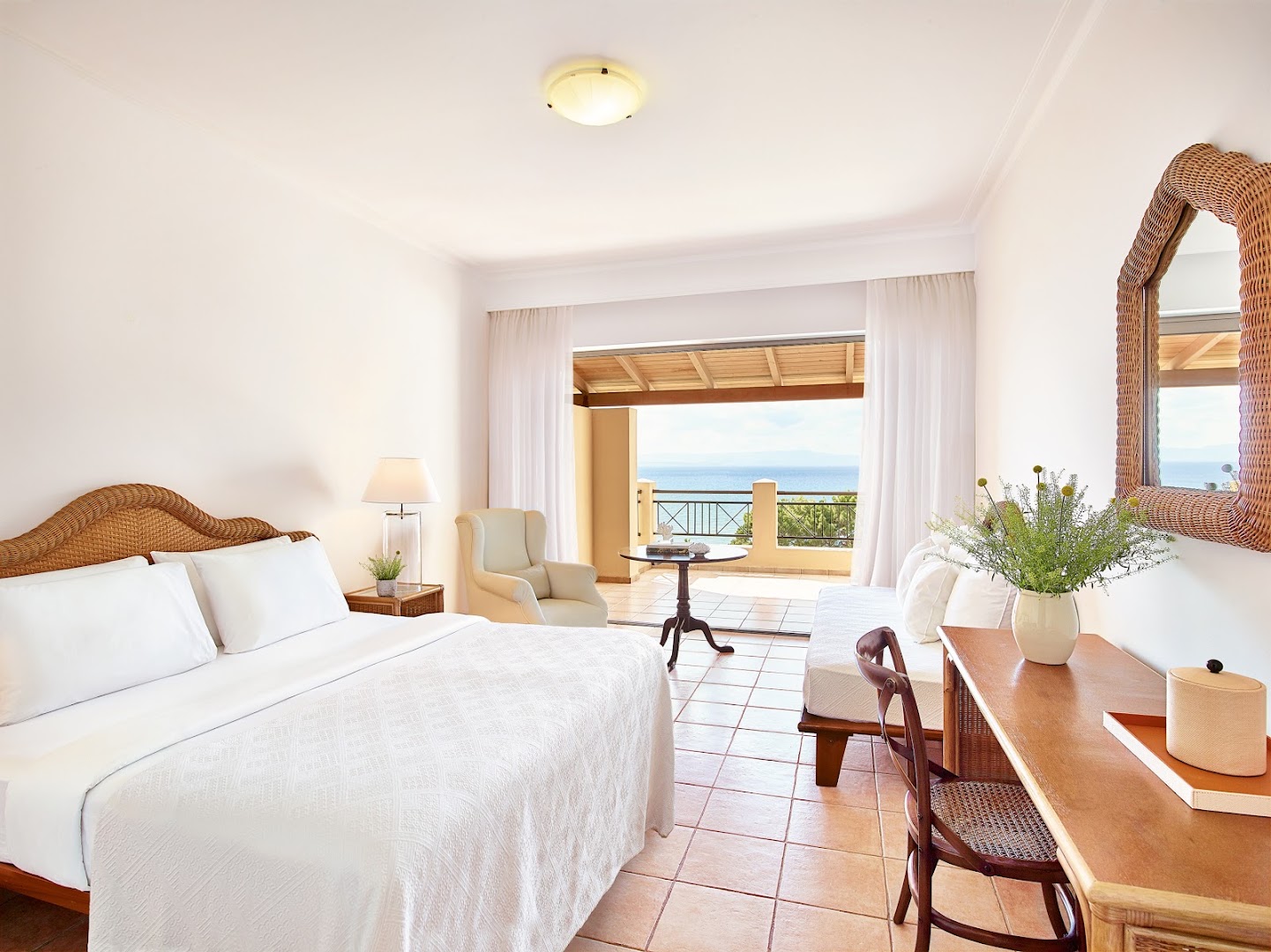 Grecotel LUXME Oasis gaišs divvietīgs numurs ar pītu gultas galvgali, atpūtas zonu un skatu uz jūru no balkona