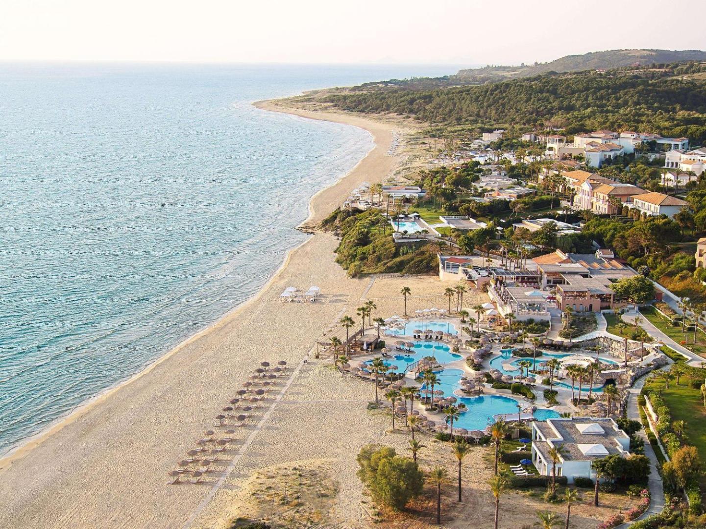 Grecotel LUXME Oasis at Riviera Olympia aerofoto uzņēmums ar plašu smilšu pludmali, baseinu kompleksu un viesnīcas ēkām Peloponēsas piekrastē.