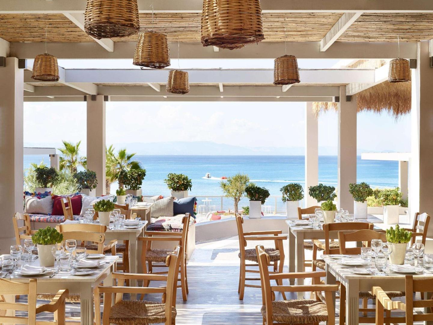 Grecotel LUXME Oasis at Riviera Olympia ēdienkartes restorāns ar skatu uz Jonijas jūru un tradicionālu koka interjeru