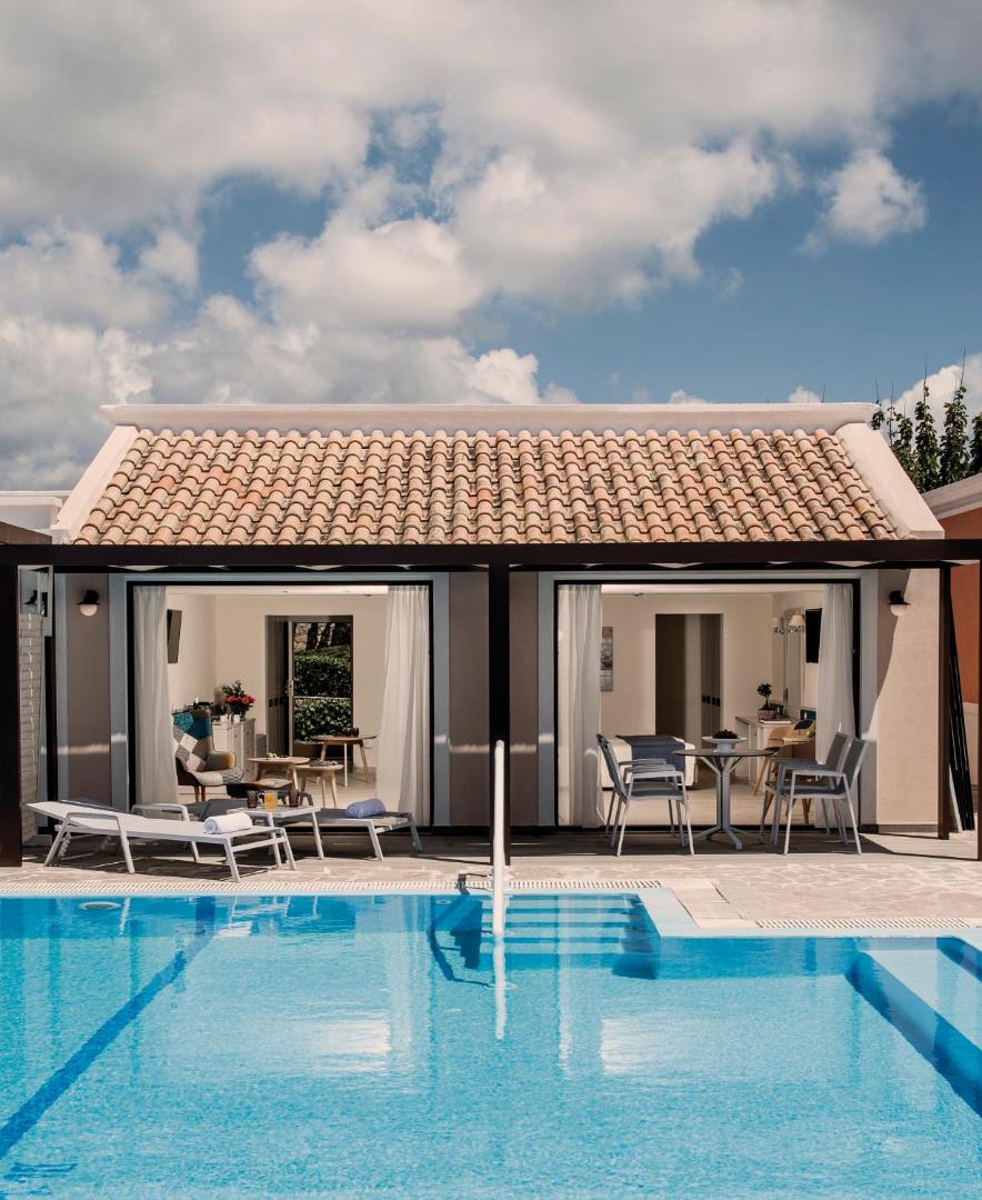 Aldemar Olympian Village bungalo tipa numurs ar privātu terasi un baseinu — gaišs interjers un tradicionāls dakstiņu jumts