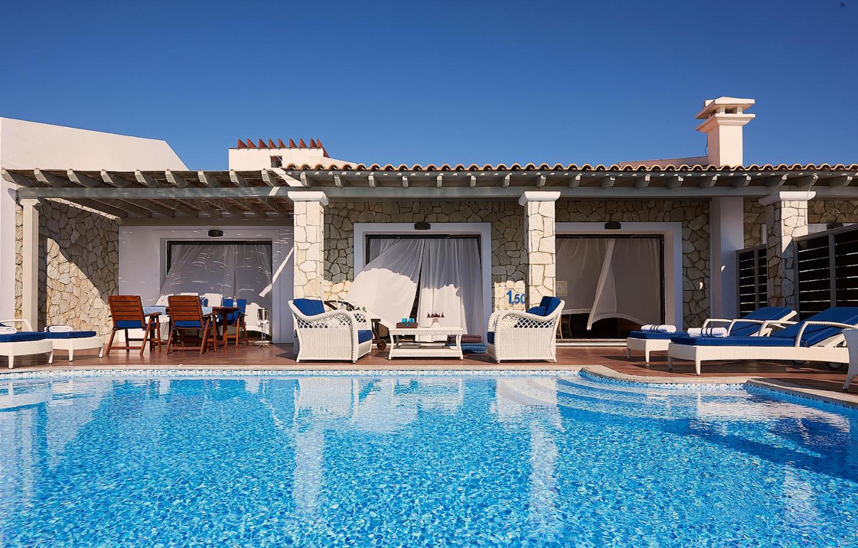 Aldemar Olympian Village numurs ar tiešu piekļuvi baseinam — akmens mūra fasāde, terase ar atpūtas krēsliem un galdiņu