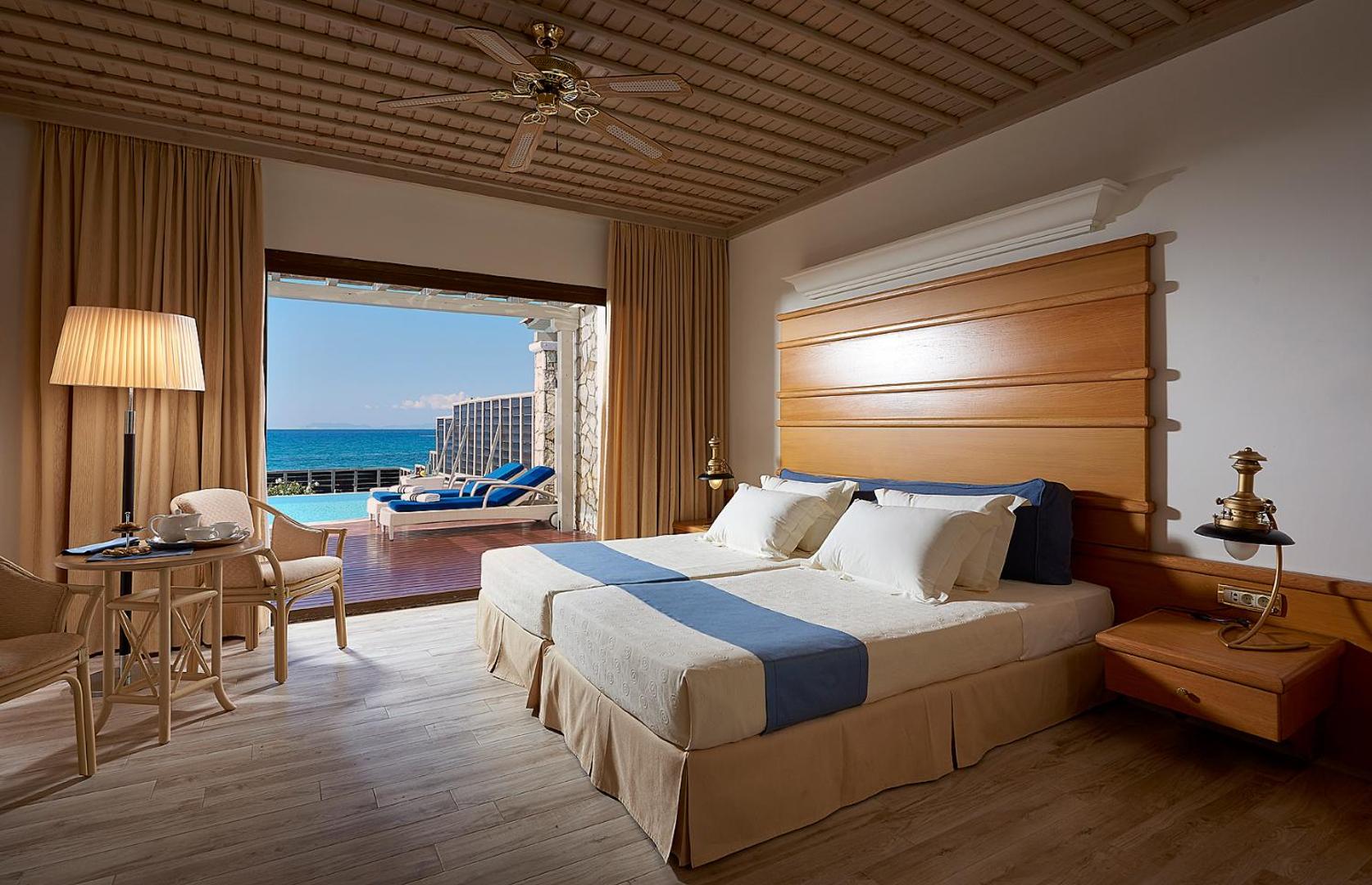 Aldemar Olympian Village numurs ar koka apdari un terasi, no kuras paveras skats uz baseinu un jūru.