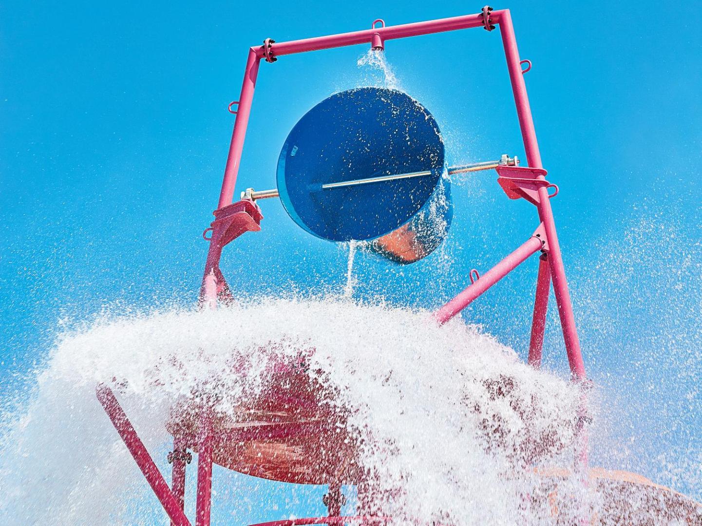 Grecotel Ilia Palms & Aqua Park bērnu akvaparka elements — liels ūdens spainis, kas gāž ūdeni, nodrošinot jautrību karstā vasaras dienā