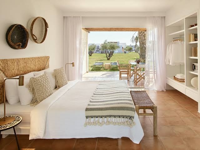 Grecotel Casa Marron gaišs viesnīcas numurs ar terasi Peloponēsā — skats uz dārzu, pīts gultas galvgalis un boho stila interjers