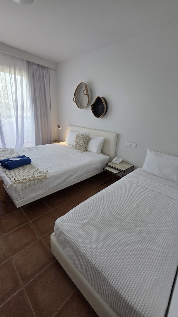 Grecotel Casa Marron gaišs numurs ar divām gultām Peloponēsā — balta gultas veļa, terakotas flīžu grīda un dekoratīvi grozi pie sienas