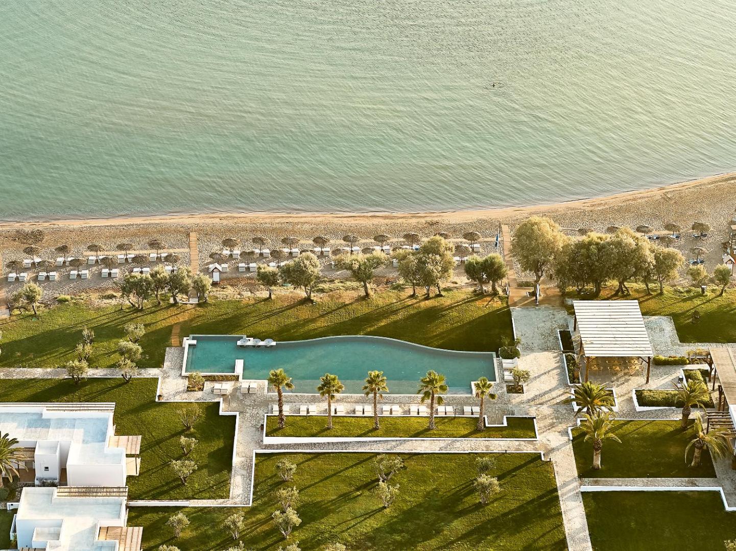 Aerofoto skats uz Grecotel Casa Marron baseinu zonu, zaļo zālienu un smilšu pludmali Peloponēsas piekrastē Grieķijā