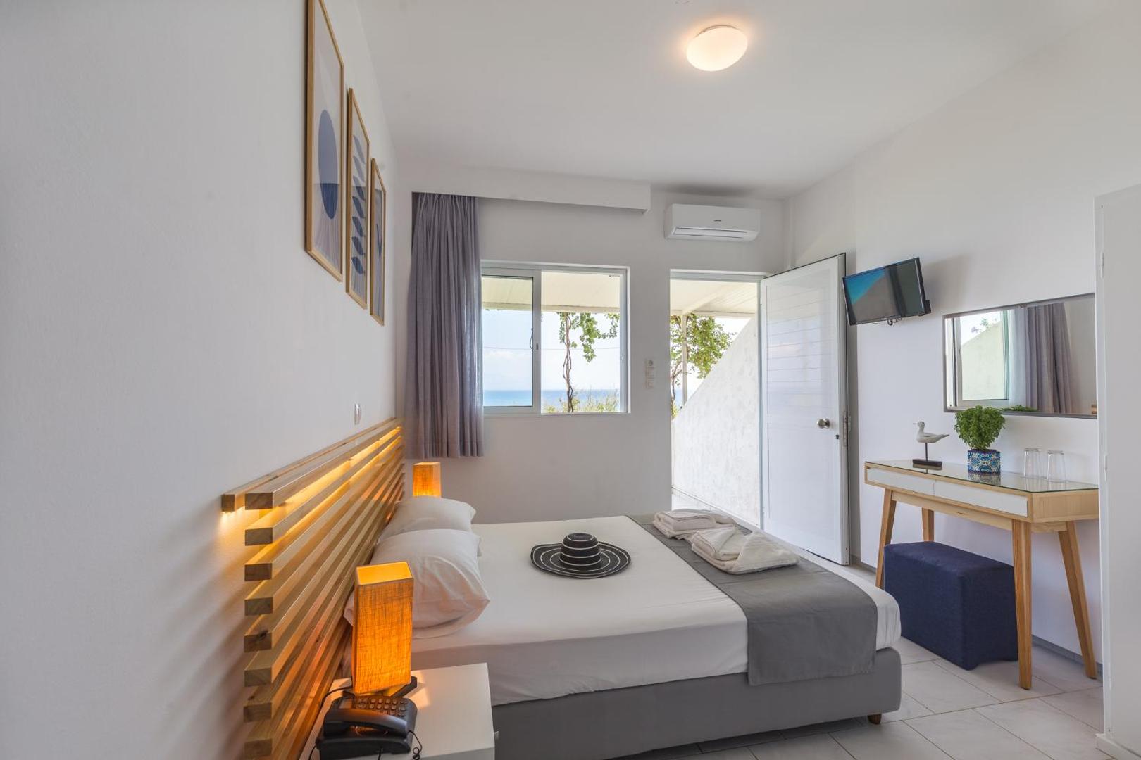 Niforeika Beach Hotel & Bungalows numura interjers ar rakstāmgaldu, spoguli un izeju uz terasi ar skatu uz dārzu un jūru
