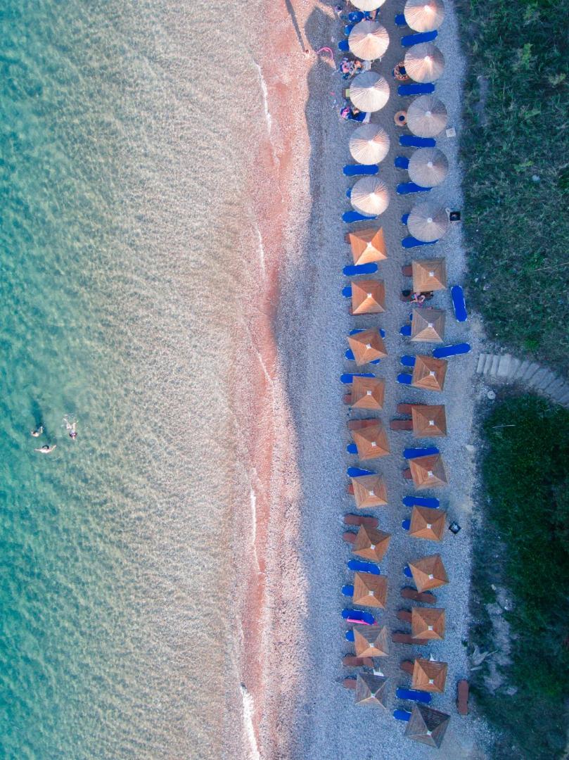 Aerofoto skats uz Niforeika Beach Hotel pludmales zonu ar sakārtotām saulessargu rindām un tirkīzzilu piekrastes ūdeni Peloponēsā