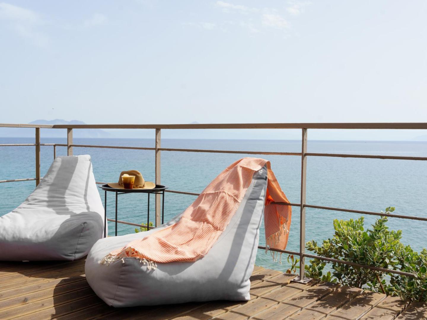 Niforeika Beach Hotel & Bungalows koka terase ar ērtiem sēžammaisiem un galdiņu tieši pie jūras krasta Peloponēsā
