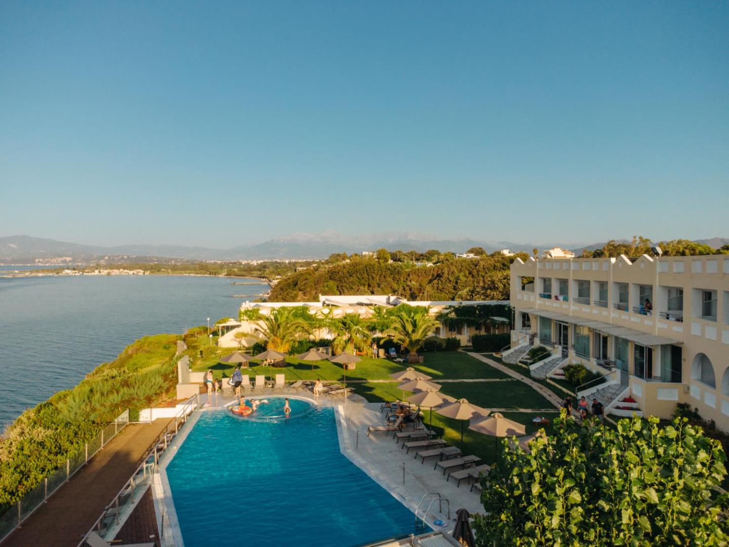 Niforeika Beach Hotel teritorijas skats no augšas — baseins, zaļš zālājs, viesnīcas korpuss un piekrastes līnija Peloponēsā