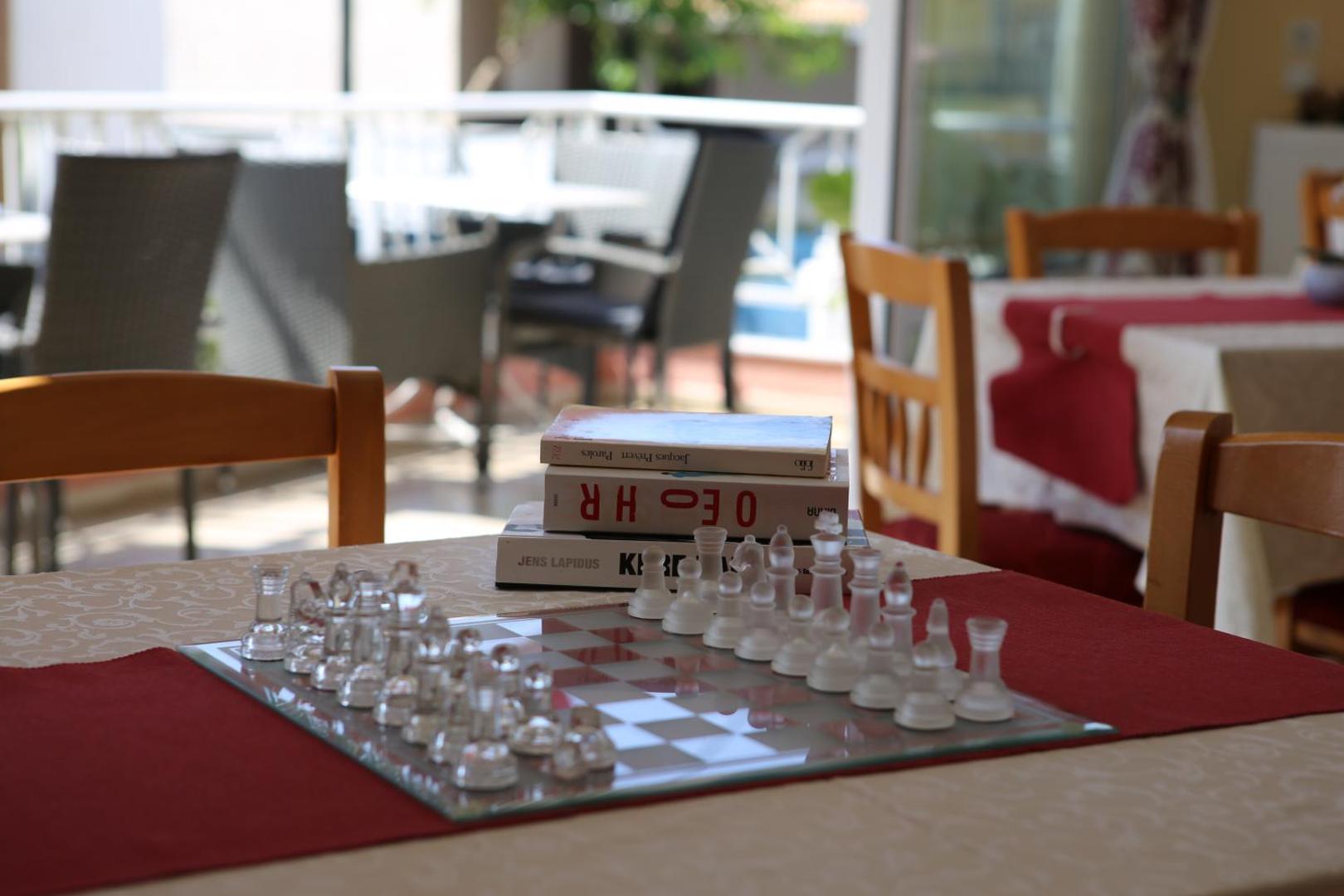 Brati II Beach Hotel atpūtas zona ar šaha galdiņu un grāmatām uz galda viesnīcas koplietošanas telpās