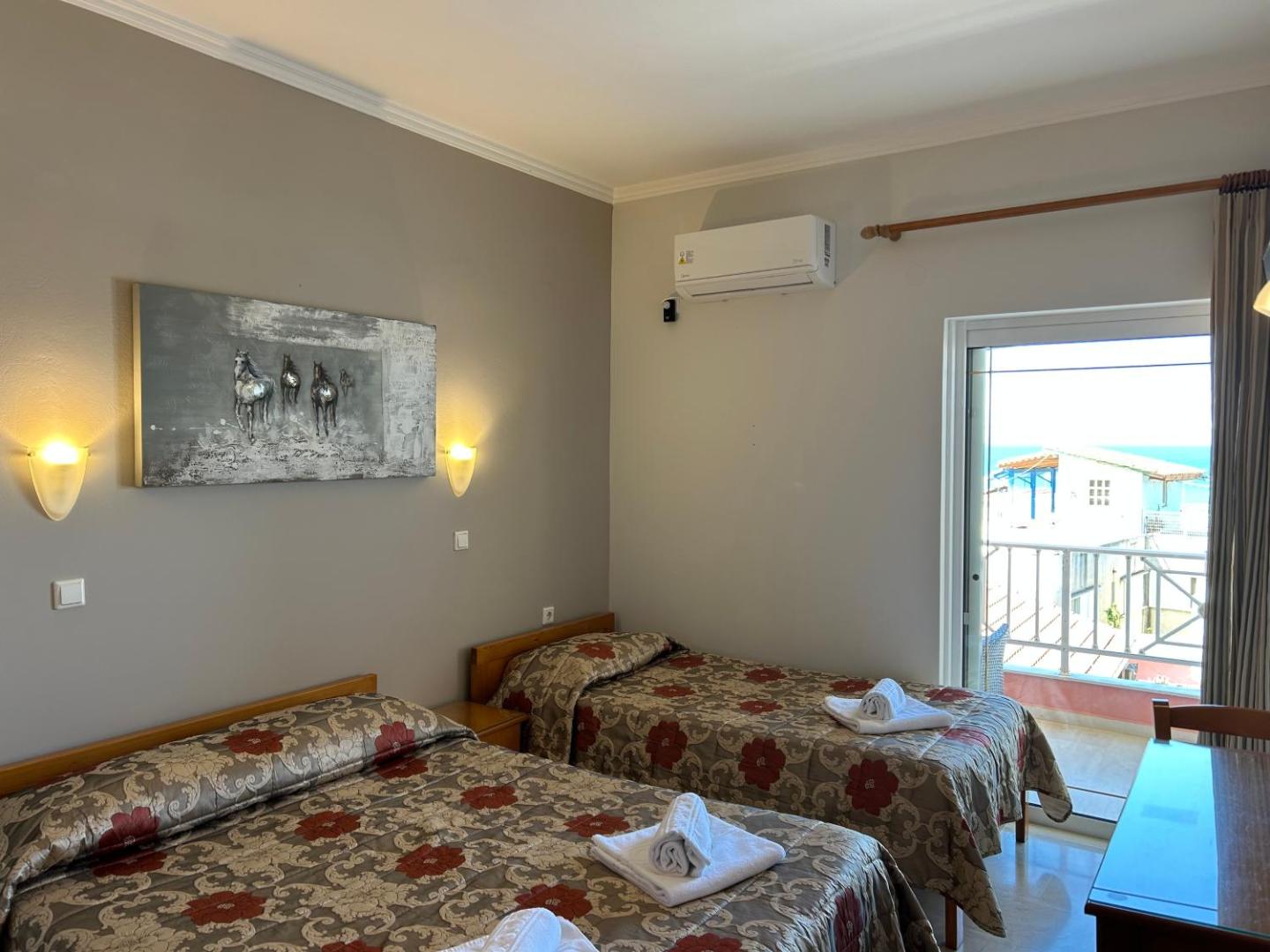Brati II Beach Hotel numura interjers ar skatu uz balkonu un jūru — divas gultas un darba galds