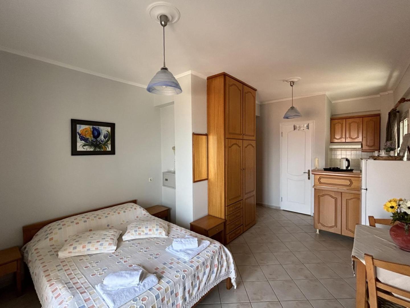 Brati II Beach Hotel studijas tipa numurs ar nelielu virtuves zonu, koka mēbelēm un flīžu grīdu Grieķijas piekrastē.