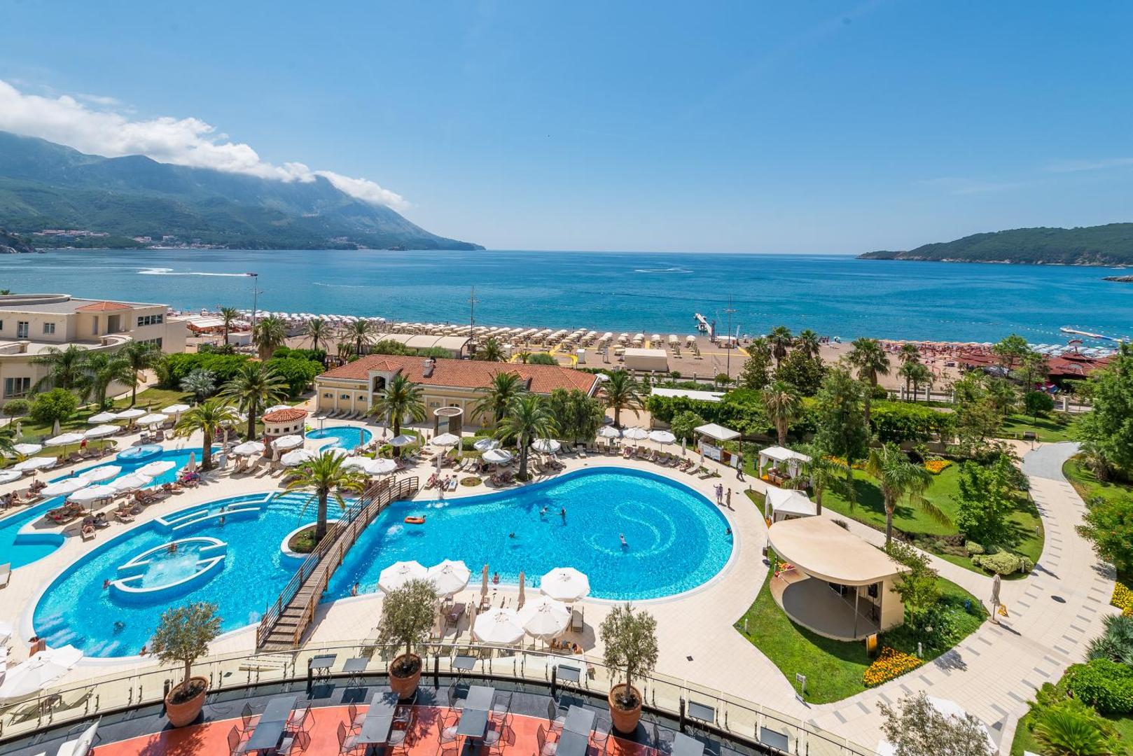 Panorāmas skats uz Splendid Conference & Spa Resort baseiniem, dārzu un Adrijas jūras piekrasti Bečiči kūrortā, Melnkalnē