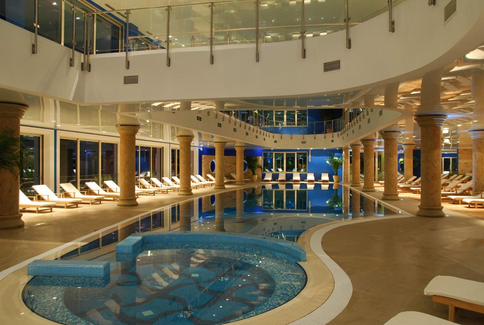 Splendid Conference & Spa Resort iespaidīgais iekštelpu baseins ar kolonnām, džakuzi zonu un atpūtas krēsliem luksusa spa centrā