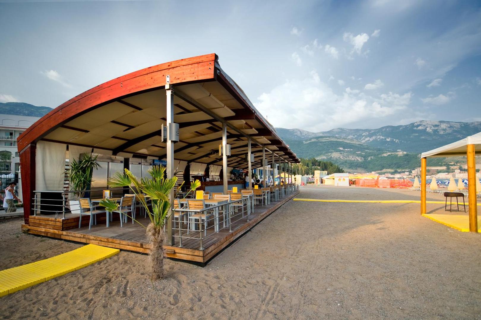 Splendid Conference & Spa Resort pludmales restorāns un bārs ar koka terasi smiltīs — skats uz kalniem un piekrastes zonu