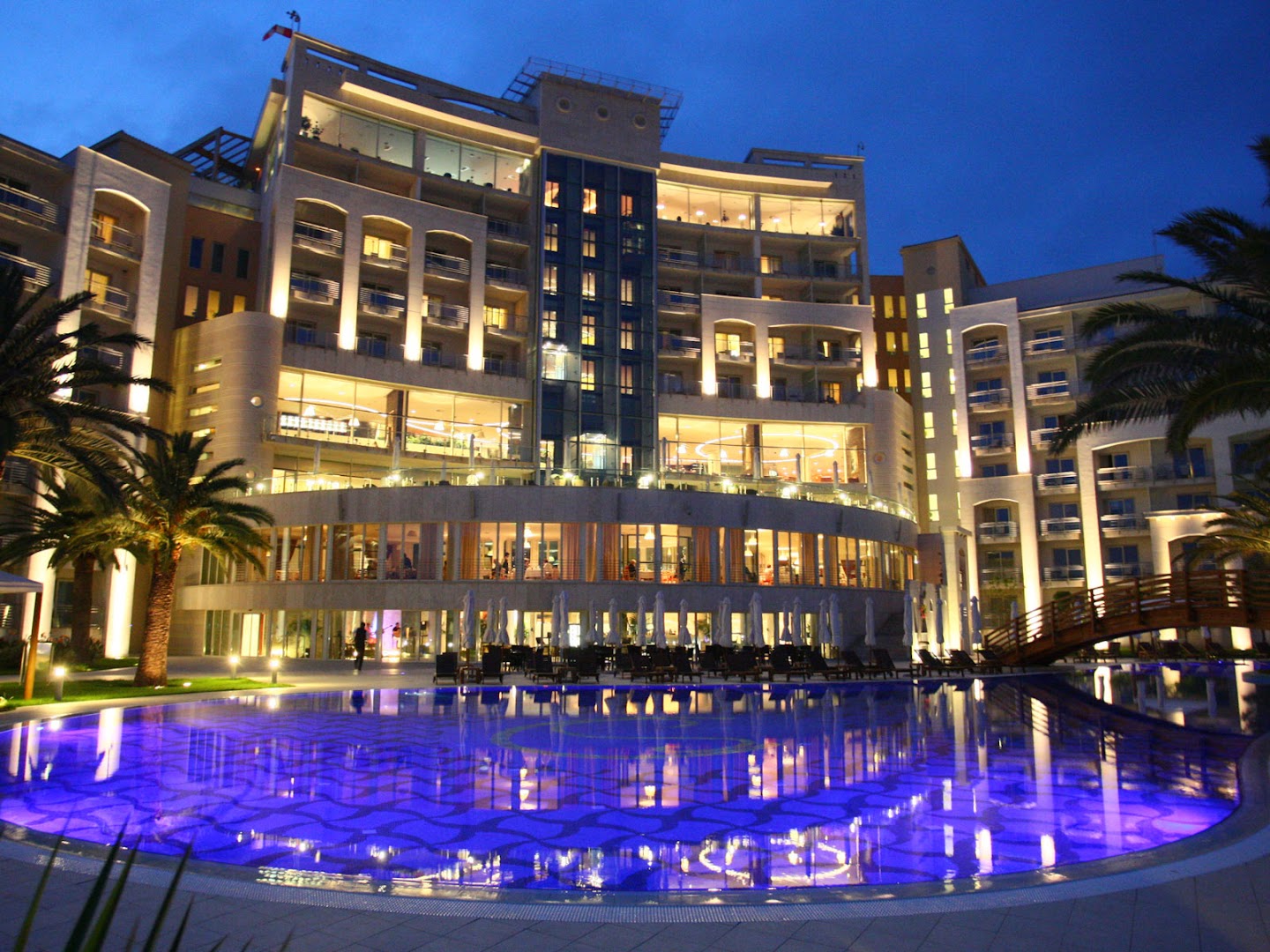 Splendid Conference & Spa Resort izgaismotā fasāde un baseins vakarā ar atspulgiem ūdenī Bečiči kūrortā