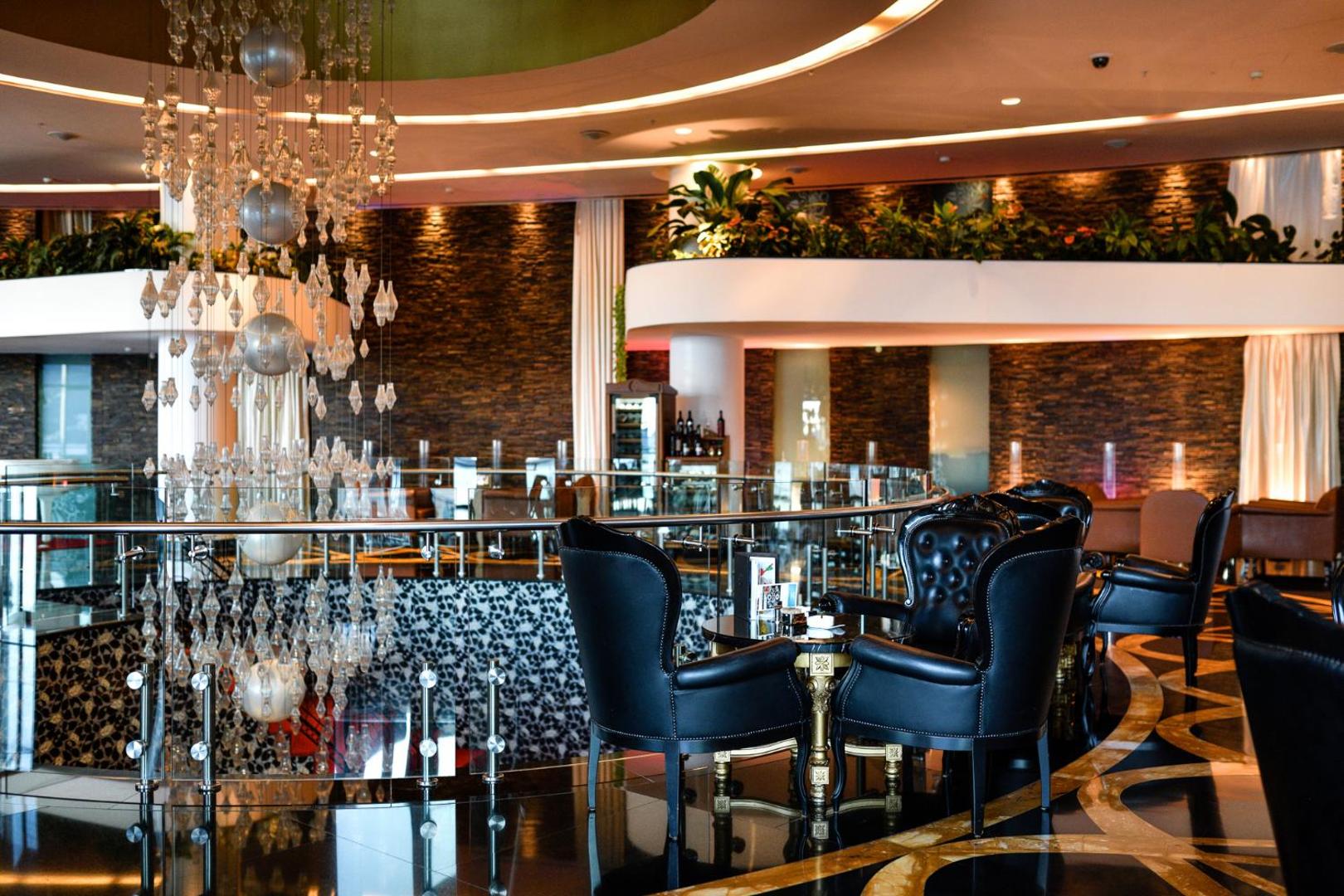 Splendid Conference & Spa Resort bāra zona ar melniem ādas krēsliem, dekoratīvām lustrām un akmens apdares sienām modernā stilā