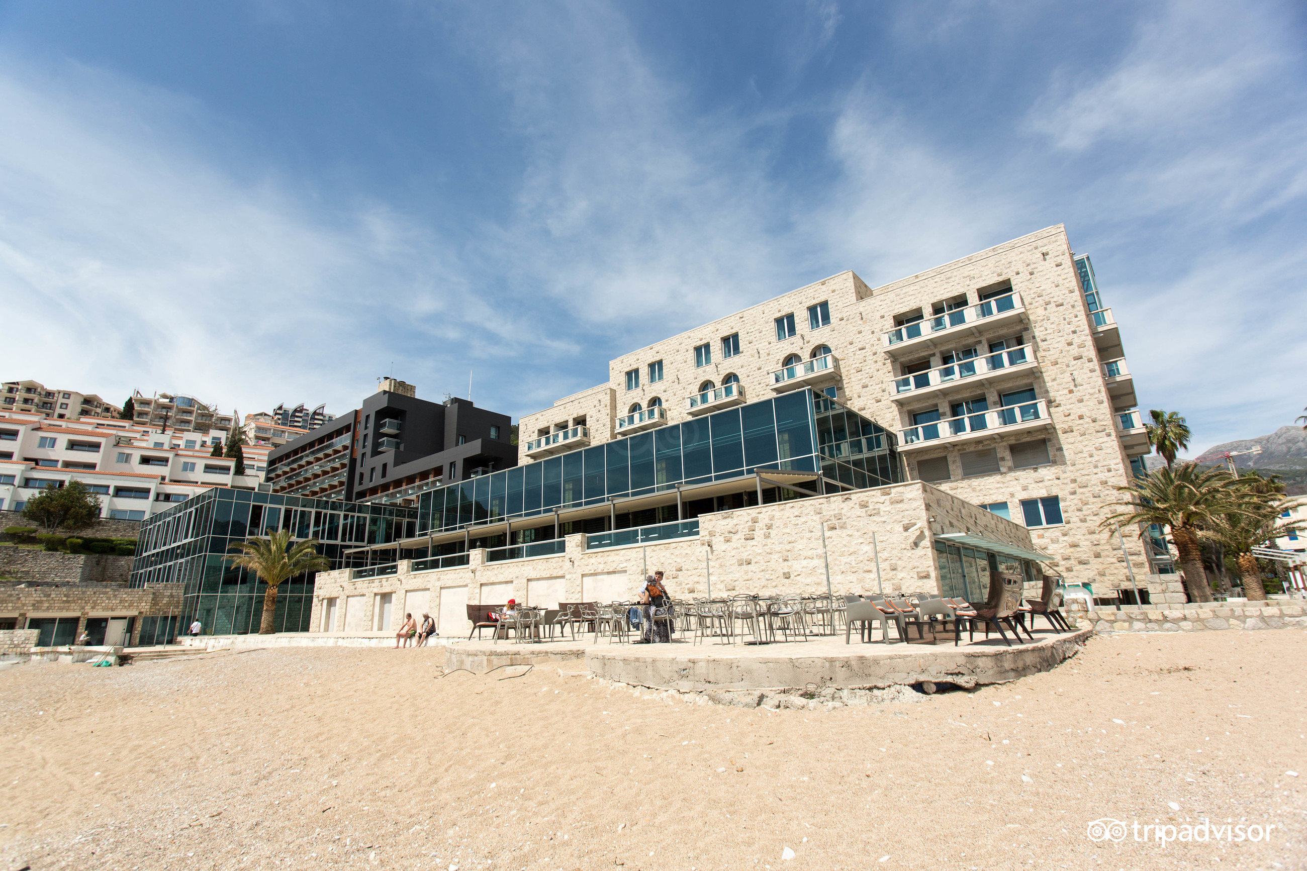 Viesnīcas Avala Resort & Villas akmens fasāde un āra terase pie pludmales — arhitektūra un atpūtas zona Budvas piekrastē