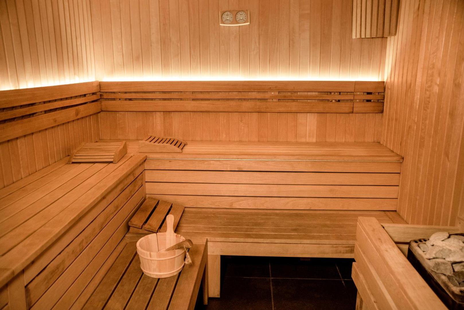 Avala Resort & Villas spa centra sauna ar gaiša koka apdari un siltu apgaismojumu — relaksācijas zona viesu atpūtai