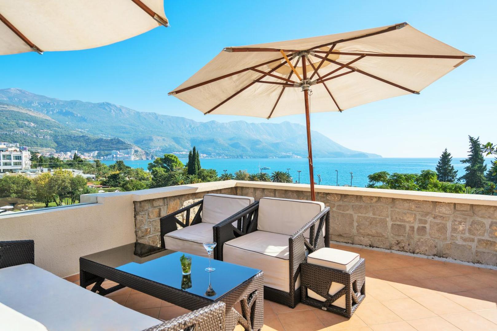Iberostar Waves Bellevue terase ar pītiem atpūtas krēsliem, saulessargu un panorāmas skatu uz Adrijas jūru un kalniem