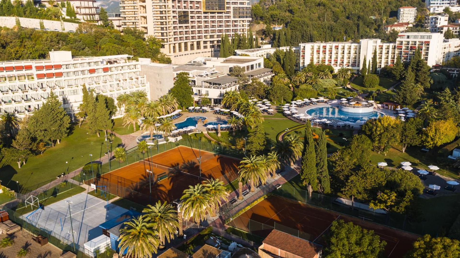Iberostar Waves Bellevue āra baseini, tenisa korti un zaļā dārza teritorija ar palmām, skatoties no augšas dienas laikā