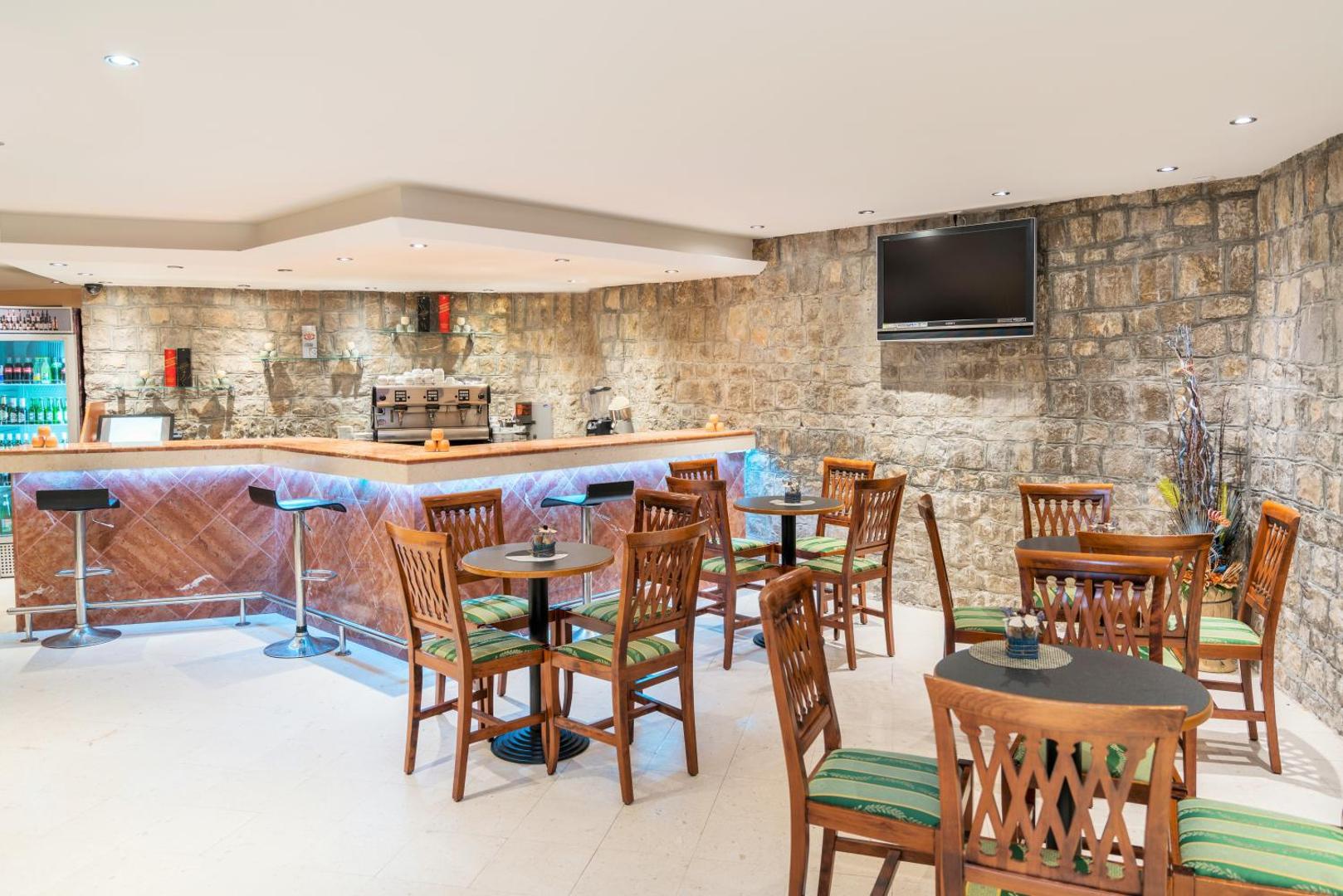 Iberostar Waves Bellevue iekštelpu bārs ar akmens mūra sienām, koka mēbelēm un mājīgu apgaismojumu vakara atpūtai