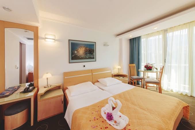 Montenegro Beach Resort klasisks viesnīcas numurs ar divām gultām, koka mēbelēm un dekoratīviem gulbjiem uz gultas
