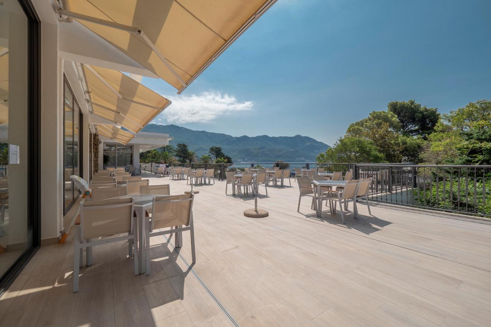 Montenegro Beach Resort plašā restorāna terase ar skatu uz Adrijas jūru un kalniem Bečiči līcī