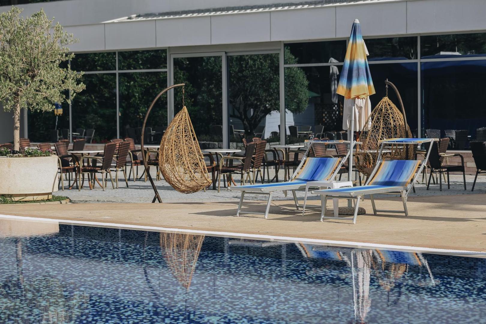 Montenegro Beach Resort atpūtas zona pie baseina ar stilīgiem piekaramajiem krēsliem un sauļošanās zviļņiem