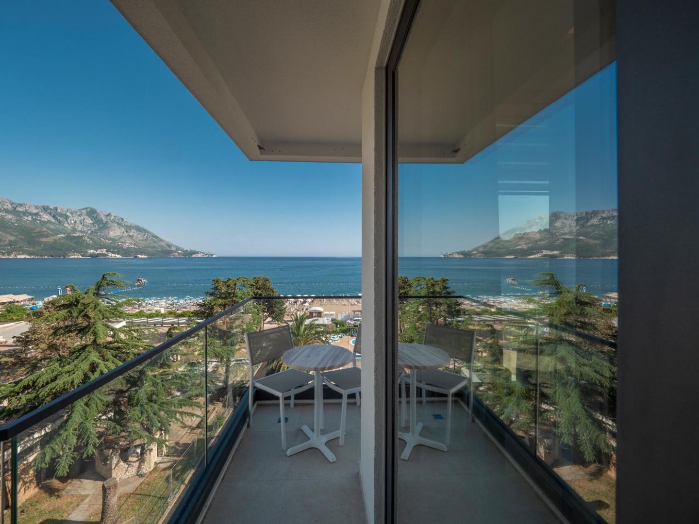Montenegro Beach Resort numura balkons ar skatu uz Adrijas jūru un kalniem Bečiči kūrortā, Melnkalnē — galds un krēsli atpūtai