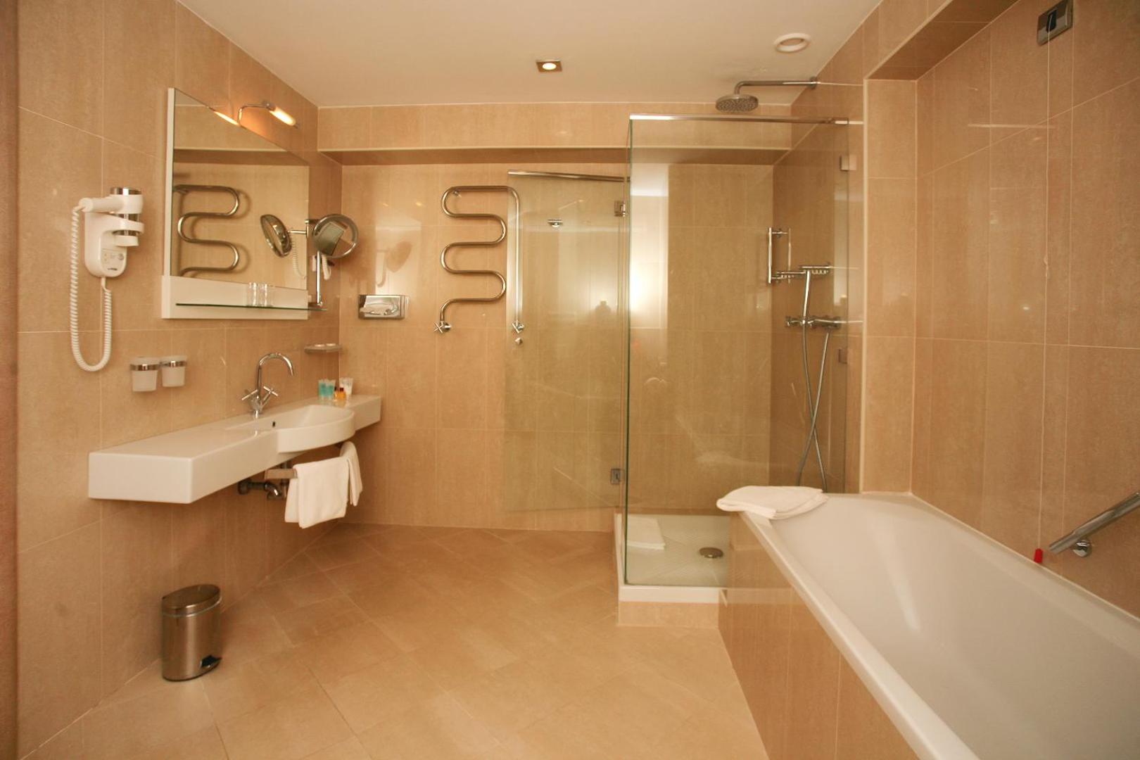 Plaša Monte Casa Spa & Wellness numura vannas istaba ar atsevišķu dušas kabīni, vannu un gaišām flīzēm