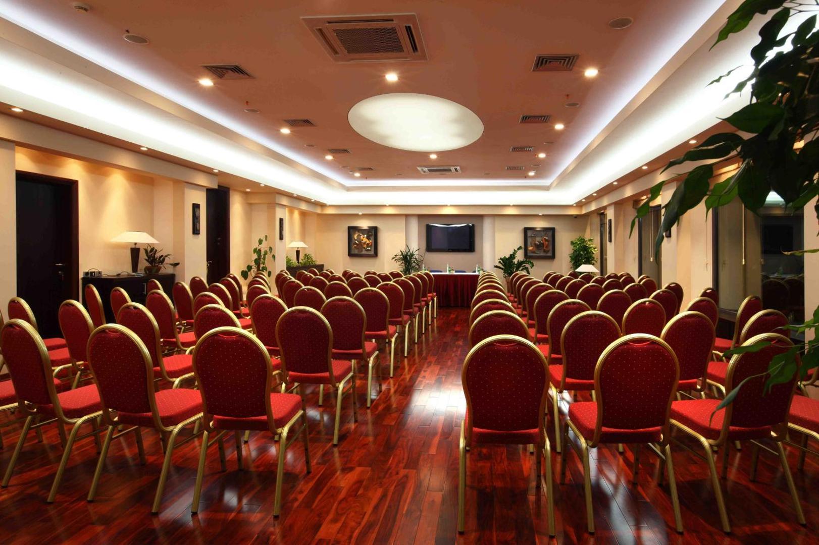 Monte Casa Spa & Wellness konferenču zāle ar sarkaniem krēsliem, koka grīdu un modernu audio-vizuālo aprīkojumu pasākumiem